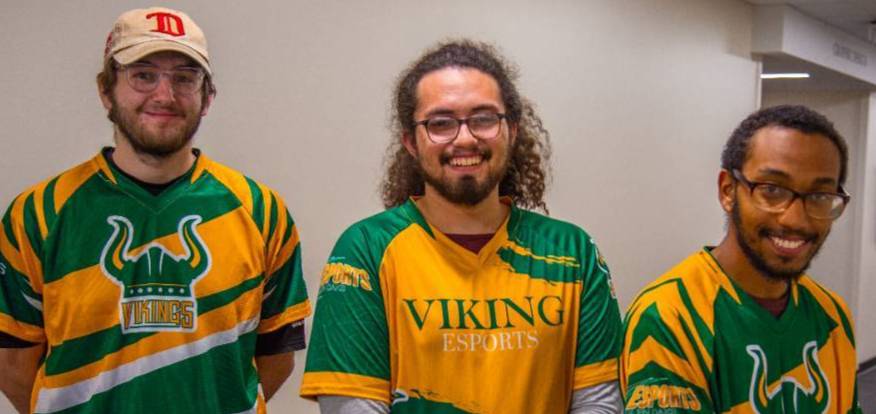 ESports gaming student sitting in front of multiple monitors playing a game, holding a controller