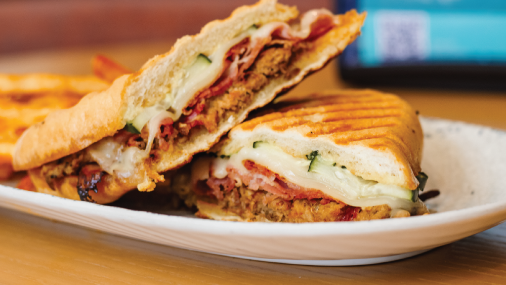 Grilled paninis sandwiched with meat and cheeses on a plate.