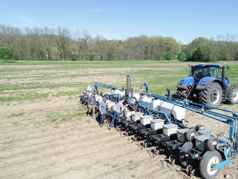 blue tractor with students loading seed
