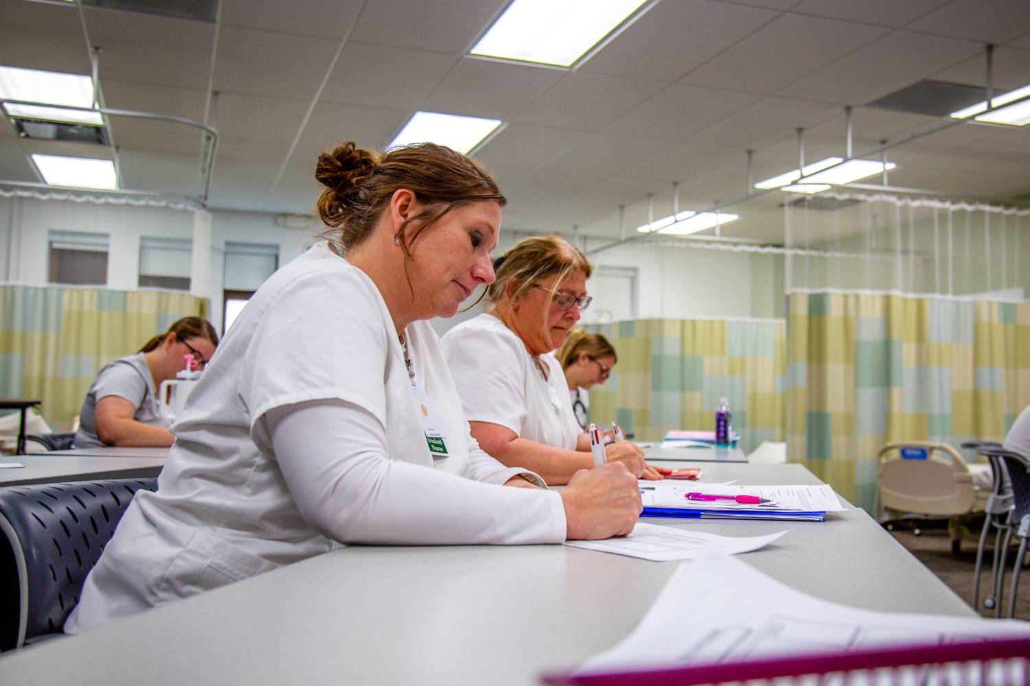 Nursing students in class, taking notes while sitting at a table