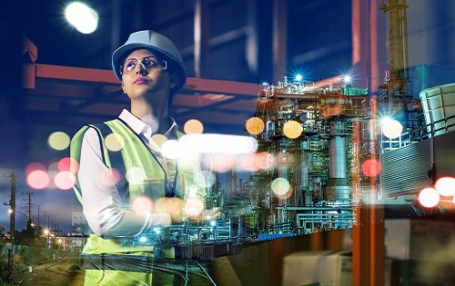 Woman standing on an industrial manufacturing site in a hard hat and vest