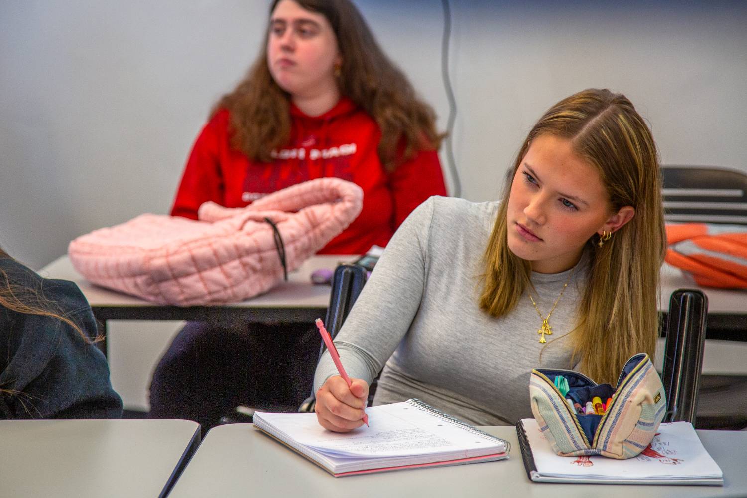 female students sitting at a desk taking notes on a notebook