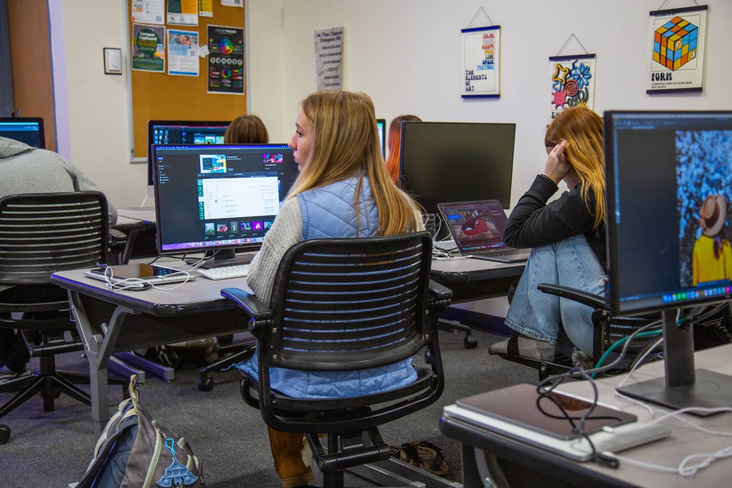students sitting in classrooms in front of computer monitors