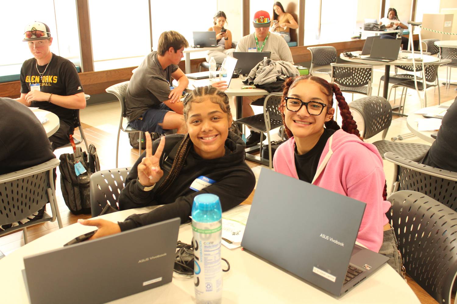 two students with laptops sitting at a table