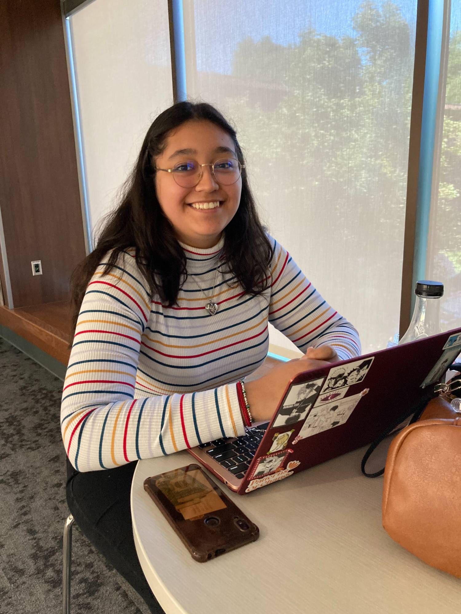 female student sitting at table with open laptop and smiling