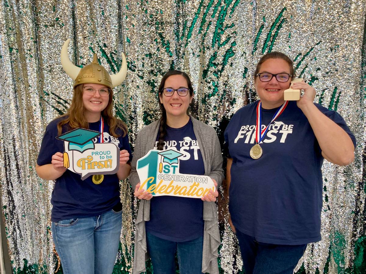 First-gen support staff standing in front of a sequin background in the photo booth holding first-gen props. These are advisors and also first-gen college attendees as well.