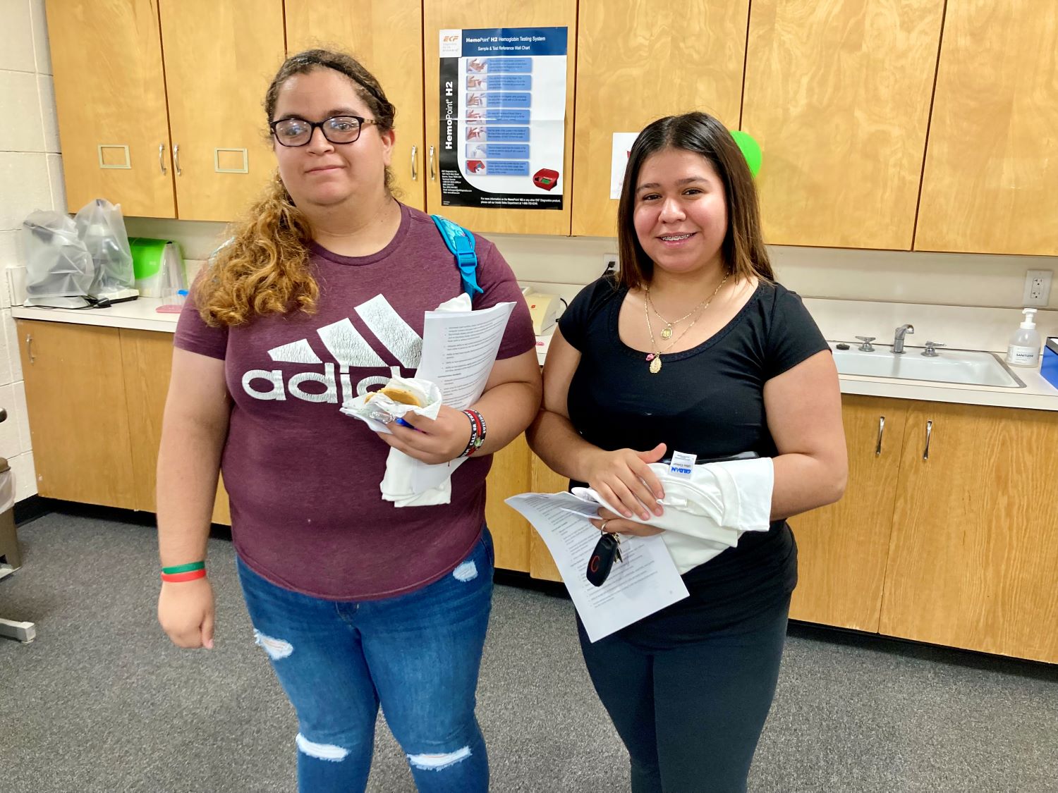 two female students standing in a classroom with a bank of cabinets behind them